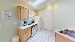 a kitchen with wooden cabinets and white appliances at Club Villas Unit 17D Villa in Sunset Beach