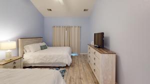 a bedroom with two beds and a television on a dresser at Club Villas Unit 17D Villa in Sunset Beach +3 photos