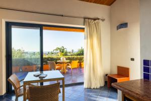 Magaggiari Hotel Resort في شينيسي: غرفة معيشة مع طاولة وكراسي وشرفة