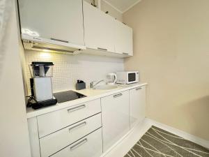 a white kitchen with a sink and a microwave at I&A Residence - Roseni tn in Tallinn