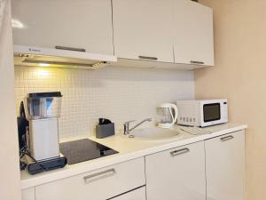 a kitchen with white cabinets and a sink and a microwave at I&A Residence - Roseni tn in Tallinn