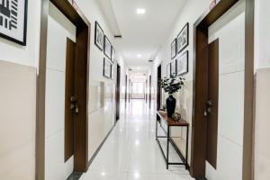 a hallway with white walls and a vase on a table at Via Sai Lodging - Nashik Railway Station in Nashik +21 photos