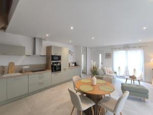 Les Dunes - Calme et Sérénité à 5 min de la Plage en voiture في Biville-sur-Mer: مطبخ وغرفة معيشة مع طاولة وكراسي