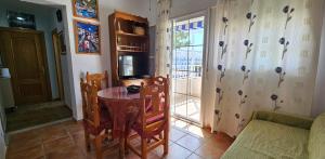 a living room with a table and a tv and a window at Apartamentos Wily y Mavi in San José