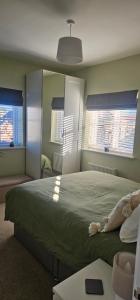 a bedroom with a large bed and two windows at Hart's Place in Leicester