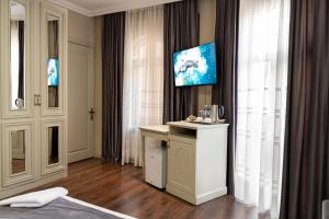 a hotel room with a desk and a tv on the wall at Parliament Hotel & Restaurant in Baku
