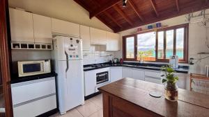 a kitchen with white appliances and a large window at Pousada Astral in Imbituba