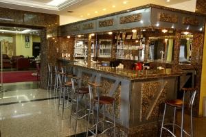 a bar with stools in a room with gold tiles at Kayhanbey Hotel in Kusadası