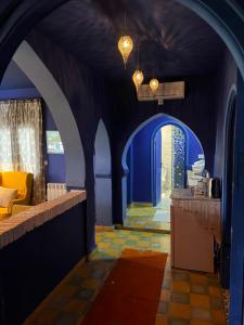 a room with blue walls and a hallway with a kitchen at Dar Elrio in Chefchaouen