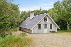 a small white house with a gambrel roof at Feriehus 1133 in Ringkøbing