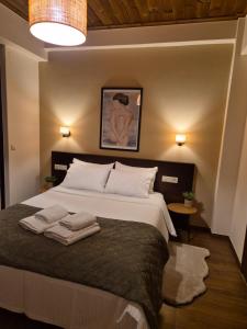 a bedroom with a large bed with two towels on it at Halasma Meteora in Kastrákion