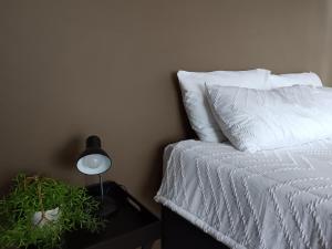 een bed met witte lakens en een lamp op een tafel bij 179 Guesthouse on Mountain Drive in Mbabane