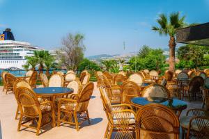 a row of tables and chairs with a cruise ship in the background at Kayhanbey Hotel in Kusadası