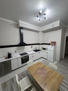 eine Küche mit weißen Schränken und einem Holztisch und Stühlen in der Unterkunft 2-room Apartment in Zaman in Atyrau