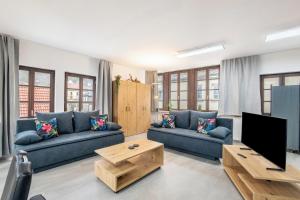 un salon avec des canapés bleus et une télévision dans l'établissement Ferienwohnung Talblick, à Pottenstein