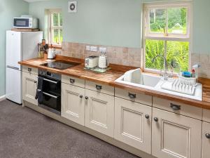 een keuken met een wastafel en een witte koelkast bij Professors Cottage in Girvan