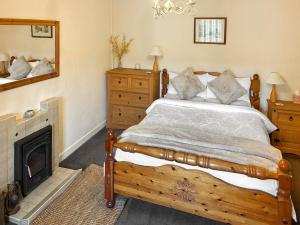 een slaapkamer met een houten bed en een open haard bij Professors Cottage in Girvan