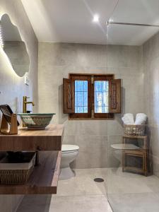 a bathroom with a toilet and a sink and a window at Cuevas El Abanico - VTAR vivienda turística de alojamiento rural in Granada