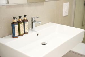 three bottles ofodorizers sit on a bathroom sink at Rooftop Tirana in Tirana