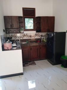 a kitchen with wooden cabinets and a black refrigerator at Free Breeze Guest & Villa in Weligama +44 photos