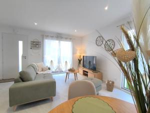 Les Dunes - Calme et Sérénité à 5 min de la Plage en voiture في Biville-sur-Mer: غرفة معيشة مع أريكة وتلفزيون