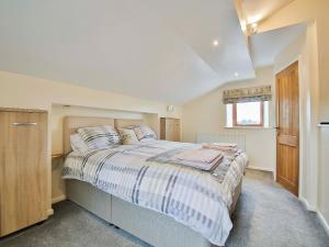 Horseshoe Cottage في Bolton by Bowland: غرفة نوم بسرير وملاءات مخططة ونافذة