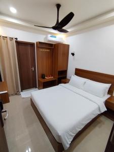 a bedroom with a white bed with a ceiling fan at Handhuveli Dhangethi in Dhangethi