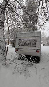 Ein im Schnee neben einem Baum geparkter Lastwagen in der Unterkunft Garden Caravan in Rovaniemi + 2 Fotos