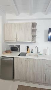 a kitchen with wooden cabinets and a sink at Idyllic Mykonos Suite w Jacuzzi and Sea Panorama in Houlakia