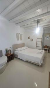 a white room with two beds and a chair at Idyllic Mykonos Suite w Jacuzzi and Sea Panorama in Houlakia +9 photos