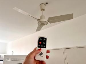 a person holding a remote control to a ceiling fan at Hostel do Alto - Fão in Esposende +149 photos