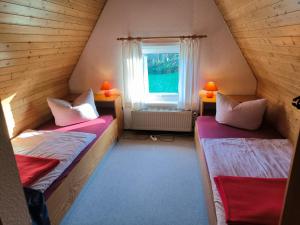 two beds in a small room with a window at Schwanensee Ferienhaus in Göhren