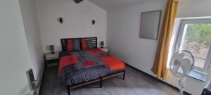 a bedroom with a bed and a fan and a window at Maison proche Grand Parc 2 Chambres in Mauléon