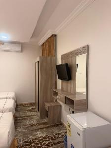 Zimmer mit einem Bett, einem TV und einem Spiegel in der Unterkunft فندق اوتاد البدر الششه in Al Khansāk