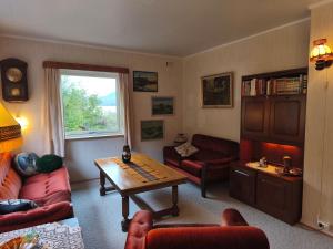 a living room with red furniture and a table at Room with Midnight-sun and Norhern-light View in Vestvågøya