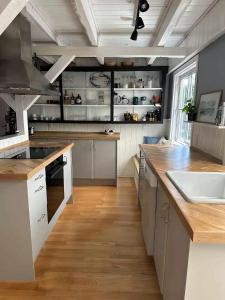 a large kitchen with white cabinets and a wooden floor at Holiday Home With Outdoor Pool, Great Location in Hornsved