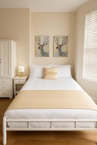 a bedroom with a large white bed with two pictures on the wall at 58 Stylish Acton Studio Fast Central Connection in London