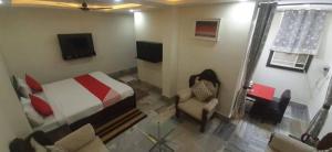 a bedroom with a bed and a chair and a tv at New Shanti Hotel in Prayagraj