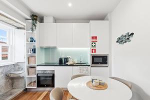 GuestReady - Charming Porto Retreat Near the Sea في بورتو: مطبخ بدولاب بيضاء وطاولة بيضاء