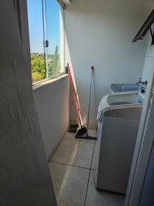 a bathroom with a mop next to a washing machine at Apartamento Larah in Cianorte