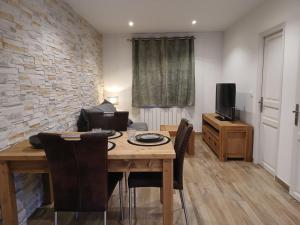 ein Wohnzimmer mit Tisch und Stühlen und einem Fernseher in der Unterkunft Escapade Champêtre in Saint-Martin-en-Bière