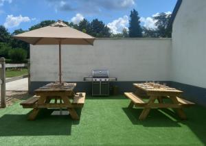 zwei Picknicktische mit einem Regenschirm auf dem Rasen in der Unterkunft Escapade Champêtre in Saint-Martin-en-Bière
