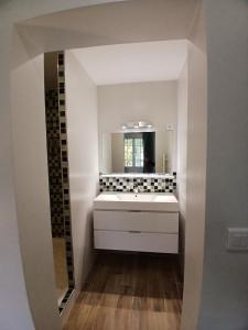 ein Badezimmer mit einem weißen Waschbecken und einem Spiegel in der Unterkunft Escapade Champêtre in Saint-Martin-en-Bière