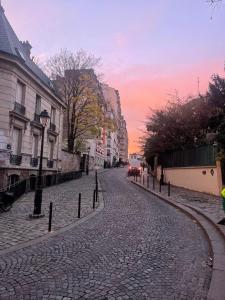 une rue pavée dans une ville au coucher du soleil dans l'établissement Les Reliefs de Montmartre, à Paris