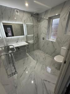 a white bathroom with a shower and a toilet at 4 Bedroom House, En-Suite, 3 Doubles 1 Single, 2 Car Parking in Colchester +9 photos