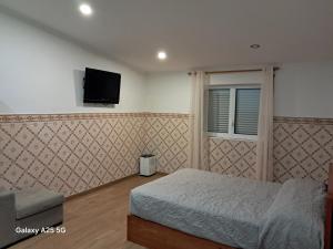 een slaapkamer met een bed en een tv aan de muur bij Casa Tio Mário in Fontinhas
