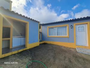 een klein blauw huisje met een garage en een deur bij Casa Tio Mário in Fontinhas