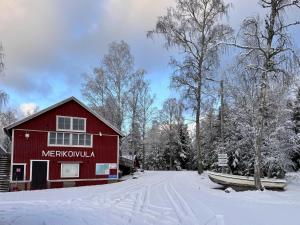 a red barn in the snow next to a road at Fishing and holiday village Merikoivula in Uusikaupunki