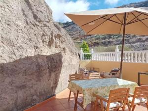 a table and chairs with an umbrella on a patio at casa La cabaña Villa Palomino in Gáldar
