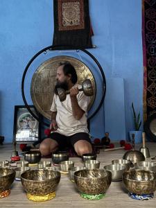 a man sitting on the floor surrounded by bowls at Baloo's Family homestay in Pokhara